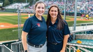 Two UNE business students pose in front of the baseball diamond at Portland's Hadlock Field